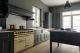 Scopri come arredare una grande cucina in stile inglese georgiano e americano coastal: gruppo cottura free standing, lavello stile farmer, ampio piano di lavoro in marmo e rivestimento a parete in doghe di legno. 